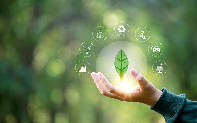 Hand hält grünes Blatt mit Symbolen für Energiequellen für erneuerbare, nachhaltige Entwicklung
